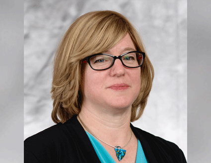 Professional photograph of presenter Laura Leibman wearing a black jacket with a turquoise blouse and glasses.